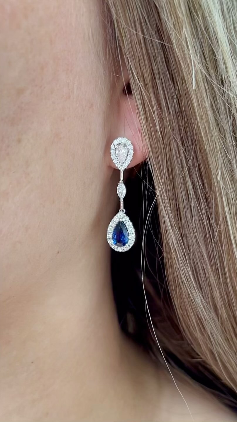 Blue teardrop gemstone earrings worn on ear